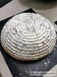 a round cake sitting on top of a black and white checkered table cloth next to a bowl