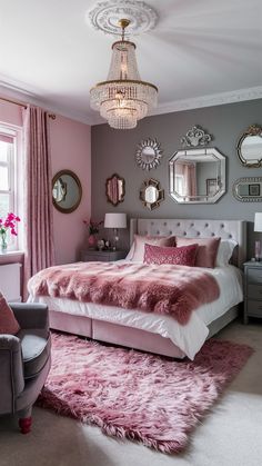 a bedroom decorated in pink and grey with a bed, chair, mirror and chandelier