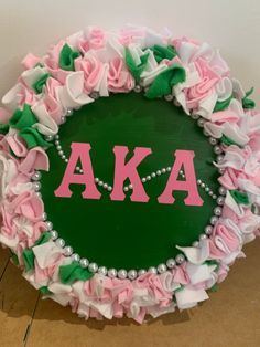 a wreath made out of pink, green and white ruffles with the letters aka on it