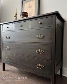 an old dresser is painted black with gold hardware