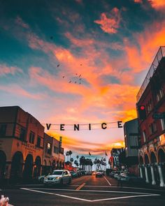 an empty street with cars parked on the side and a sign that says venice above it