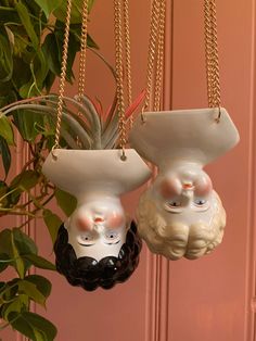 two ceramic pots with faces hanging from chains