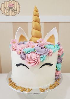 a white cake decorated with flowers and a unicorn's face