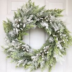 a wreath is hanging on the front door with snowflakes and pine cones around it