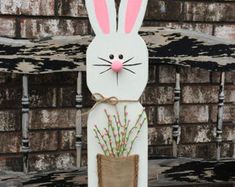 a white rabbit sitting on top of a wooden chair with flowers in it's pocket