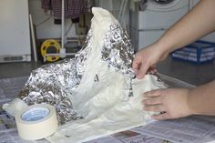 someone is making a cake with tin foil on top of the paper and wrapping around it