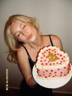 a woman holding a heart shaped cake in front of her face