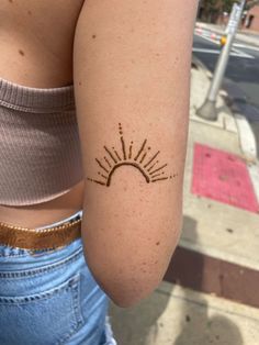 a woman's arm with a sun tattoo on her left shoulder and the back of her right arm