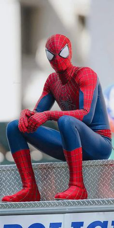 a spider man is sitting on the back of a pick up truck with his legs crossed