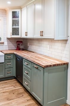 a kitchen with white cabinets and wooden counter tops