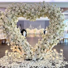 a large heart shaped arrangement with flowers and candles on the floor at a wedding reception