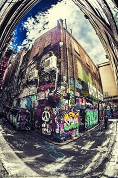 a building covered in graffiti under a cloudy blue sky