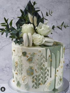 a white and green decorated cake with flowers on the top is sitting on a table