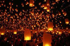 many people are flying lanterns in the dark