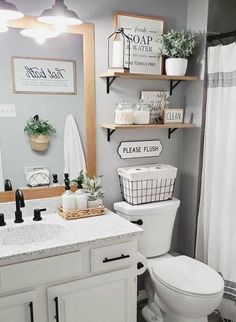 a white toilet sitting under a bathroom mirror next to a sink and shower curtain in a bathroom