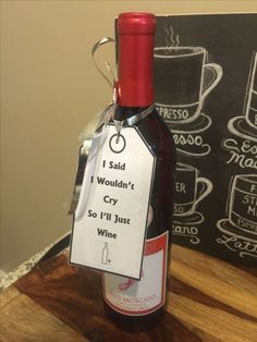 a bottle of wine with a tag attached to it sitting on a table next to a chalkboard