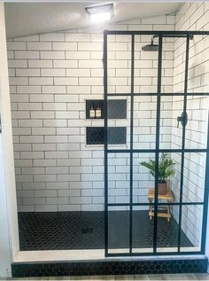 a bathroom with black and white tile walls, flooring and a glass shower door