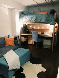 a loft bed sitting next to a blue couch in a living room under a ladder