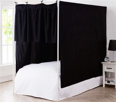 a black canopy bed in a white room with hardwood floors and window sill on the side