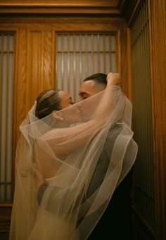 a bride and groom embracing each other under a veil