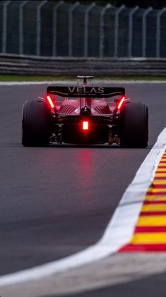 a red race car driving on a track with lights on it's front wheels