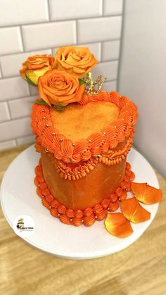 there is a cake with orange frosting and flowers on the top, sitting on a white plate