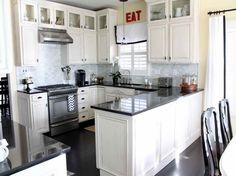 a large kitchen with white cabinets and black counter tops, an island in the middle