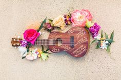 a ukulele with flowers and writing on it is laying on the ground next to a guitar