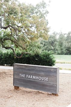 the farmhouse sign in front of a tree