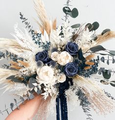 a blue and white flower arrangement in someone's hand