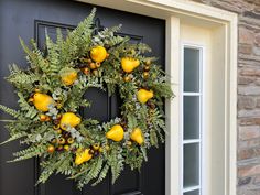 a wreath on the front door of a house decorated with yellow flowers and greenery