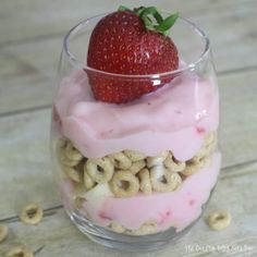 a strawberry sitting on top of some cereal in a glass