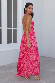 a woman in a long pink dress is looking back at the camera while wearing high heels