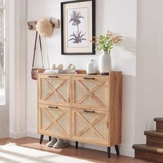 a wooden cabinet sitting in front of a window next to a stair case and potted plant