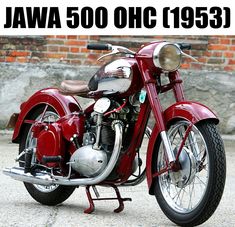 a red motorcycle parked on top of a cement floor next to a brick wall with the words jaw 500 ohc 1953