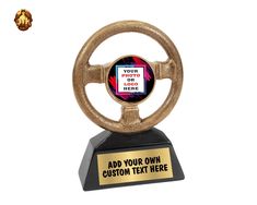 a gold colored steering wheel trophy with a black base and an inscription that reads, add your own custom text here