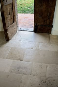 an open door leading to a yard with grass in the back ground and brick walkway