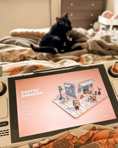 a nintendo wii game system sitting on top of a bed next to a black cat