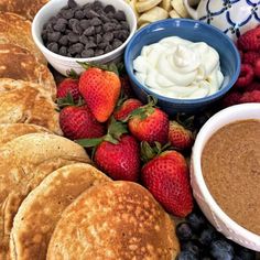 some pancakes, berries, chocolate chips and yogurt are arranged on a platter