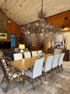 a dining room table with white chairs and a chandelier hanging from the ceiling