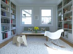 a living room filled with lots of bookshelves and furniture next to a window