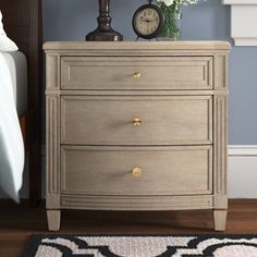 a bedroom with a bed, nightstand and clock on top of the dresser in front of it