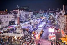 an aerial view of a christmas market in the middle of a city street at night