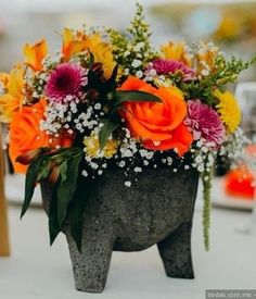 an elephant shaped vase with flowers in it sitting on top of a white table cloth