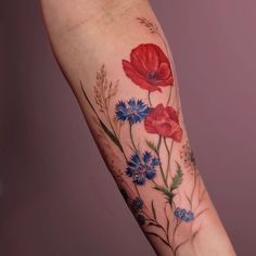 a woman's arm with red, blue and white flowers on the inside of it