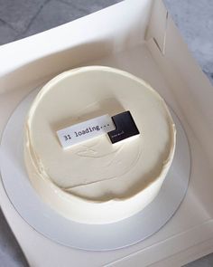 a white cake in a box with a tag on it