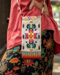 a woman is holding a cross - stitch purse