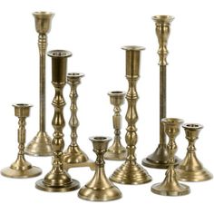 an assortment of brass colored candlesticks on a white background