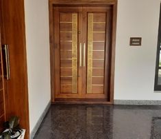 a large wooden door sitting next to a window on top of a white wall in a room