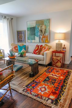 a living room filled with lots of furniture and colorful rugs on top of a hard wood floor